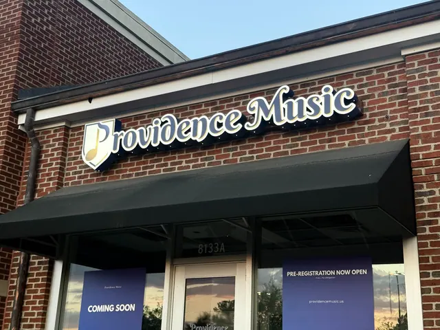 Illuminated Providence Music letters and music-note emblem mounted above a brick storefront awning.