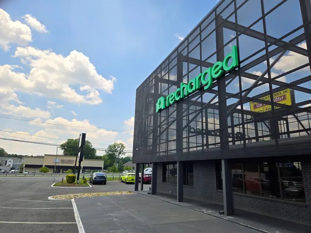 Bright green Recharged letters across a dark exterior facade.