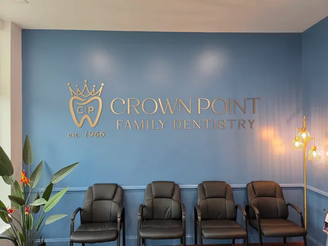 Gold CrownPoint Family Dentistry lettering and crown emblem on a blue waiting-room wall, with seating, a plant and warm lighting.
