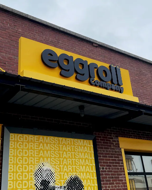 Eggroll Company’s yellow exterior sign and matching yellow graphics across the storefront windows.