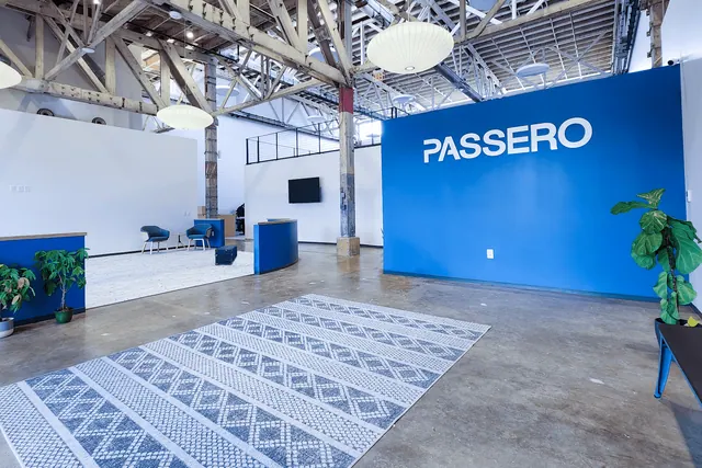 PASSERO lettering on a blue reception wall in a bright, open lobby.