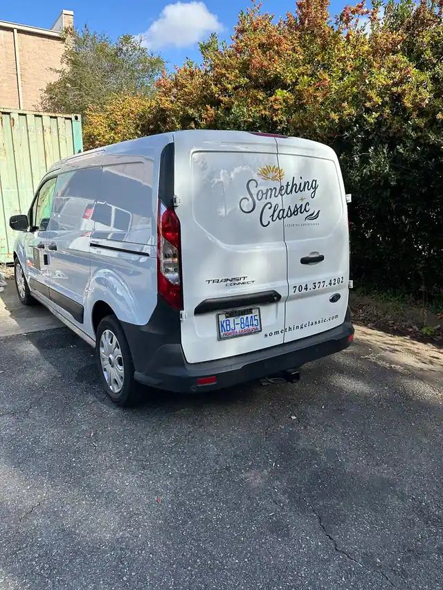 Something Classic catering name, phone number and website on the rear doors of a white delivery van.